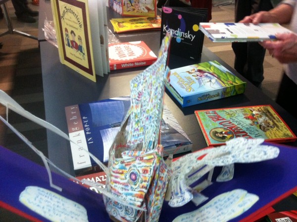 Crowded shot of open book and standing books.